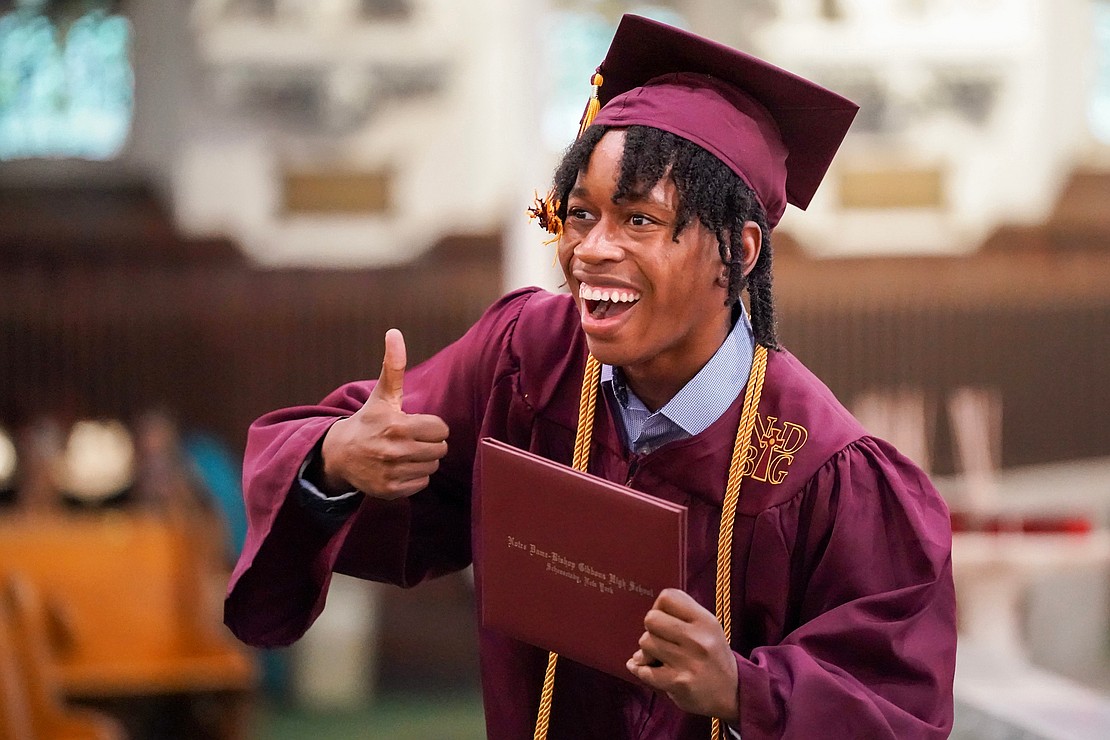Graduate Hasani Evans receives his diploma and gives a thumbs up when he spots his family during Notre Dame–Bishop Gibbons' Commencement Exercises on June 7 at St. John the Evangelist in Schenectady. (Cindy Schultz photo for The Evangelist)