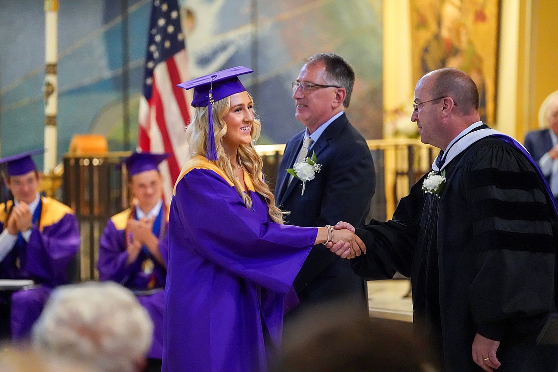 Graduate Aila Cartier, center, shakes hands with superintendent Christopher Bott, right, when she receives her diploma during Saratoga Catholic Central’s commencement exercises on Friday June 27, 2024, at St. Clement’s Church in Saratoga Springs, N.Y.  Cindy Schultz for The Evangelist