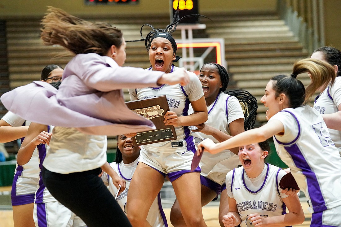 Tatavia Turpin, center, holds the plaque when coach Audra DiBacco jumps in as Catholic Central celebrates their 62-48 win over Holy Names in the Section II Class A final basketball game on Saturday, March 2, 2024, at Hudson Valley Community College in Troy, N.Y. Ms. Turpin scored her 1,000th career point during the game.  Cindy Schultz for The Evangelist