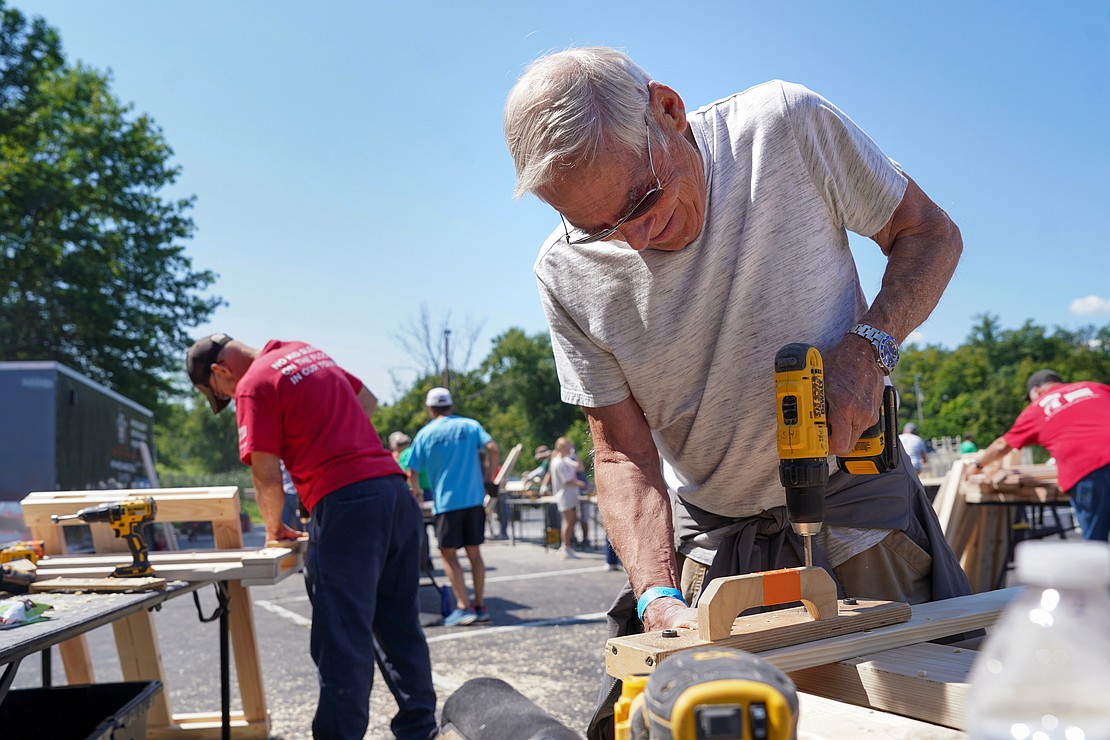 Brian Fear uses a screw gun to assembly bed frame pieces as part of the Sleep in Heavenly Peace project on Aug. 2 at St. Michael the Archangel Church in Troy. Parishioners and volunteers assembled headboards, footboards and sideboards needed to make bed frames for children. (Cindy Schultz photo for The Evangelist)