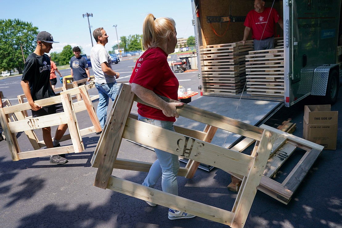 Sarah Hurley, (c.) a core crew member with Sleep in Heavenly Peace, helps load bed frame pieces onto a truck on Aug. 2 at St. Michael the Archangel Church in Troy. Parishioners and volunteers assembled headboards, footboards and sideboards needed to make bed frames for children. (Cindy Schultz photo for The Evangelist)