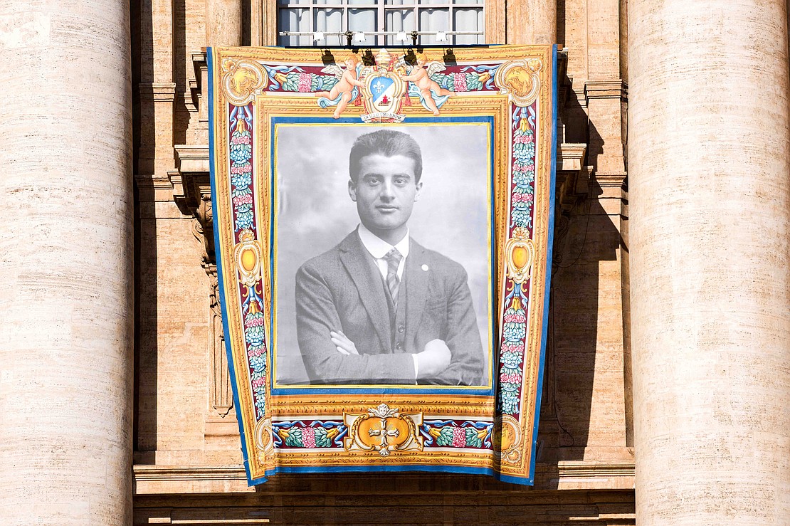 A tapestry depicting St. Pier Giorgio Frassati hangs from the facade of St. Peter’s Basilica during the Mass for his canonization at the Vatican Sept. 7, 2025. (CNS photo/Lola Gomez)