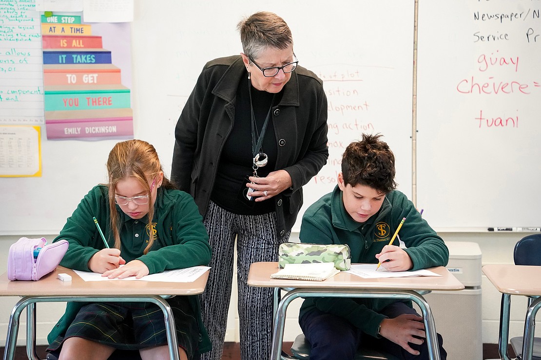 English teacher Jane Wingle \assists third-graders Evelyn Keuterman (l.) and Peter McAvoy with their Epic Reading Program on Sept. 11 at St. Thomas the Apostle School in Delmar. (Cindy Schultz photo for The Evangelist)
