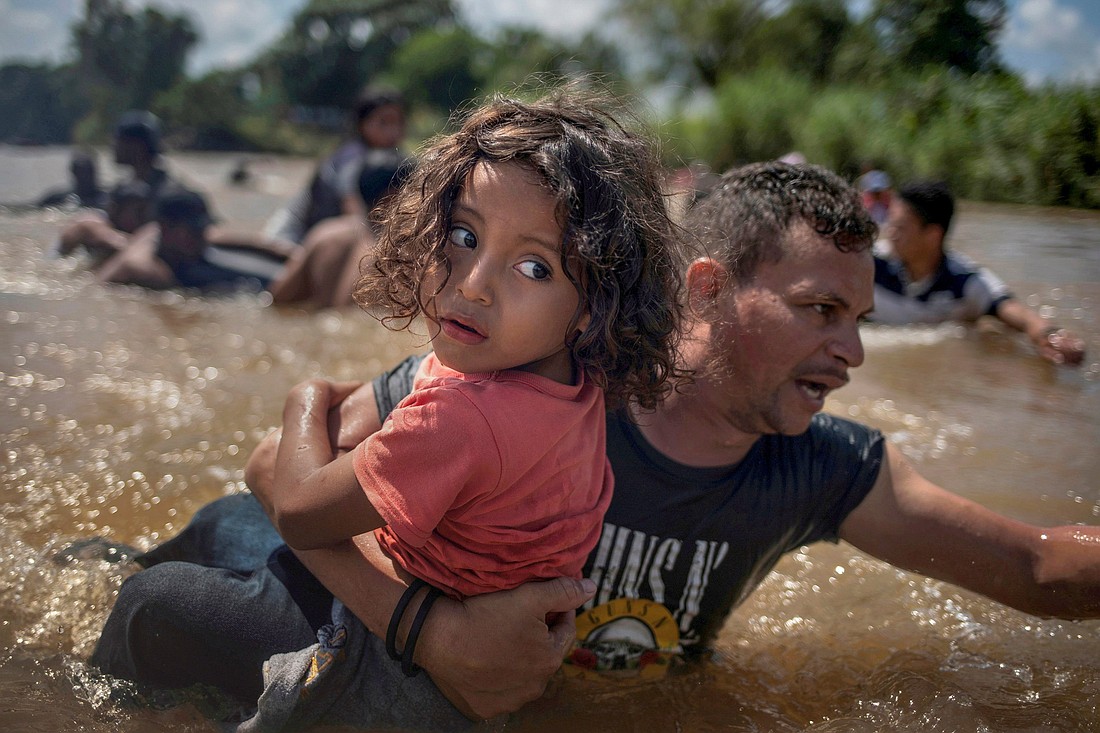 Honduran migrant Luis Acosta carries 5-year-old Angel Jesus through the Suchiate River near Tapachula, Mexico, Oct. 29, 2018. (CNS photo/Adrees Latif, Reuters)