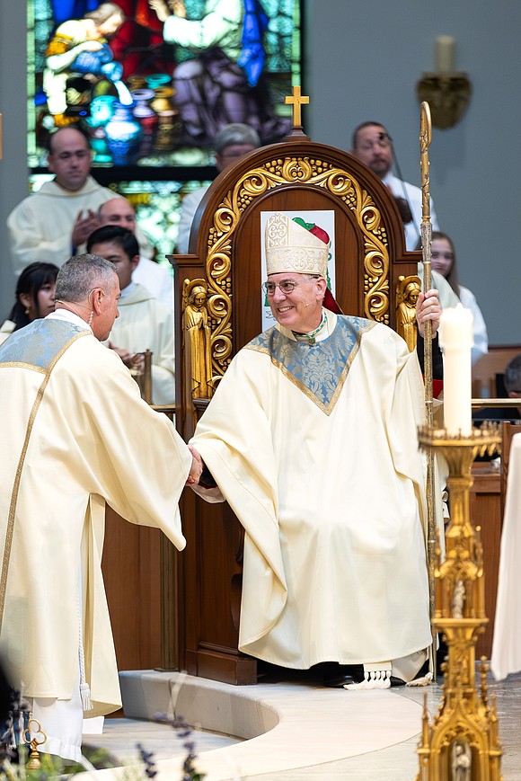 Bishop Mark W. O'Connell shakes hands with Deacon Paul LeBlanc after he is seated in the cathedra (Bishop's Chair) and given his crozier. (Patrick Dodson photo)
