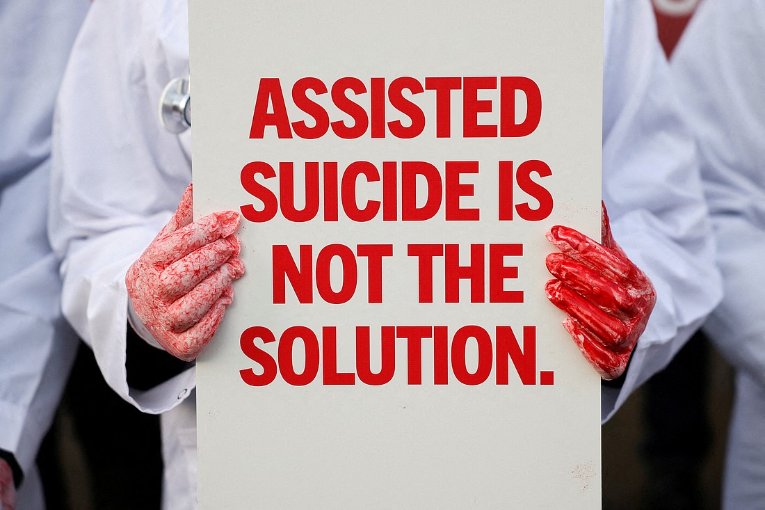 A protester holds a placard outside the Parliament in London Nov. 29, 2024, as British lawmakers debate a physician-assisted suicide bill. The House of Commons passed the bill 314 to 291, a majority of just 23 votes, on June 20, 2025. The measure now proceeds to a debate and vote in the House of Lords. (OSV News photo/Mina Kim, Reuters)