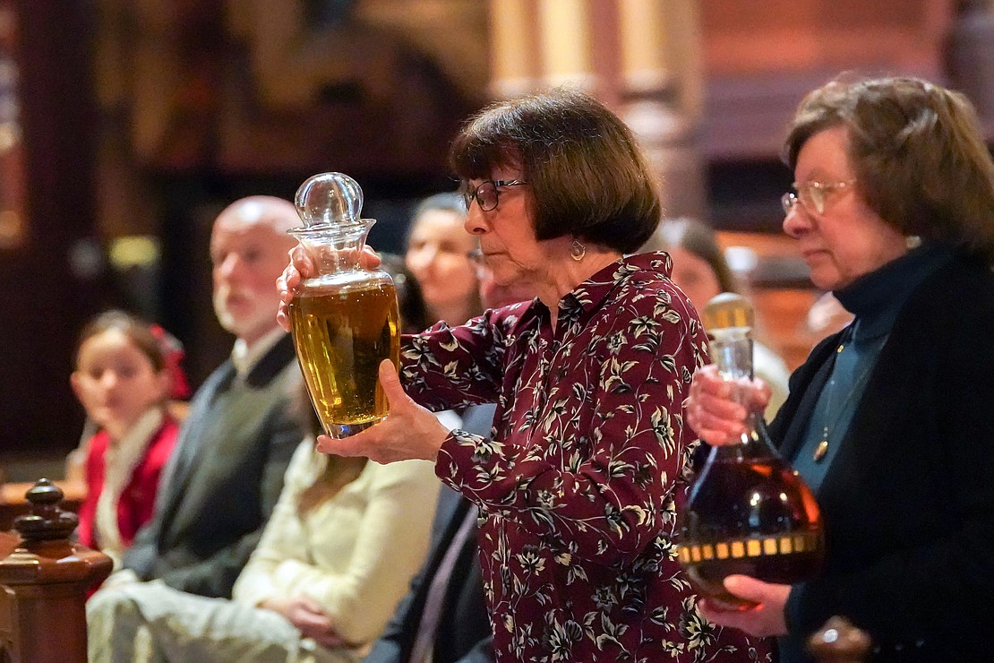 Andrea Freeman (c.) carries the oil and Millie Selby (r.) carries the balsam oil to the altar during the Chrism Mass on March 30 at the Cathedral of Immaculate Conception in Albany. (Cindy Schultz photo for The Evangelist)