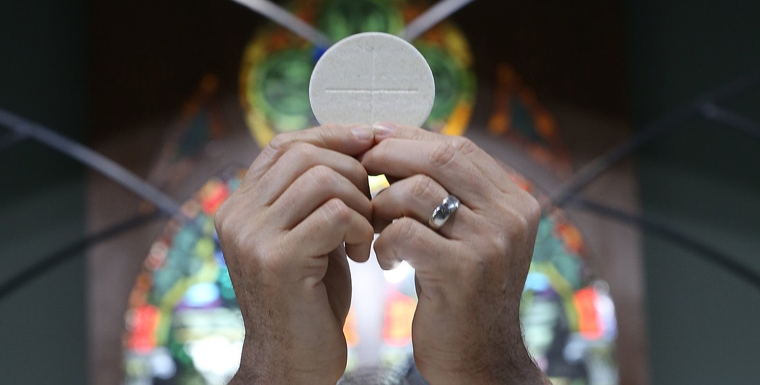 A priest raises the Eucharist in this illustration. (OSV News photo/CNS file, Bob Roller).