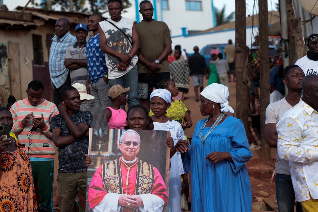 People gather next to an image of Pope Leo XIV after he arrived at Yaoundé Nsimalen International Airport in Cameroon April 15, 2026. Pope Leo is scheduled to meet with Cameroon religious and political leaders, traditional chiefs, peacemakers, as well as faithful during his April 15-18 visit. (OSV News photo/Luc Gnago, Reuters)