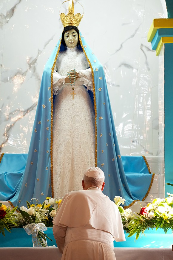 Pope Leo XIV places a bouquet at the base of a Marian statue as he visits the Sanctuary of Our Lady of Muxima in Muxima, Angola, April 19, 2026. (CNS photo/Lola Gomez)