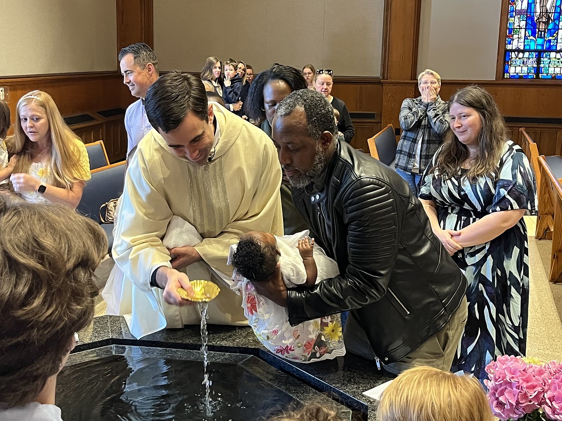 Father Matt Duclos, pastor of St. Thomas the Apostle Church, baptizes baby Naomi, the younger sister of Liam, a first-grade student at St. Thomas the Apostle School. (Emily Benson photo)