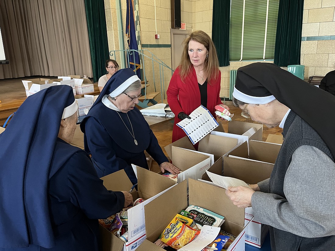 Mother Mary Louise Kane, PBVM, (from l.), Sister James Marie Carras, PBVM, Jodie O’Connell-Pankos, and Sister Rosemary Ann Cueno, CR, help pack care packages at St. Colman’s School to send to O’Connell-Pankos’ daughter, Shayla Pullaro. (Emily Benson photo)