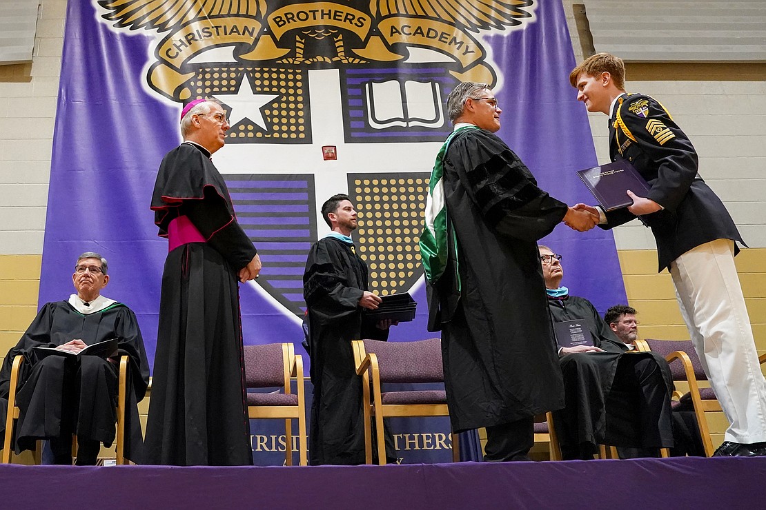 Graduate Jack Deucker receives his diploma from school president James Schlegel as Bishop Mark O'Connell looks on during commencement commencement exercises on May 29 at Christian Brothers Academy in Colonie. (Cindy Schultz photo for The Evangelist)