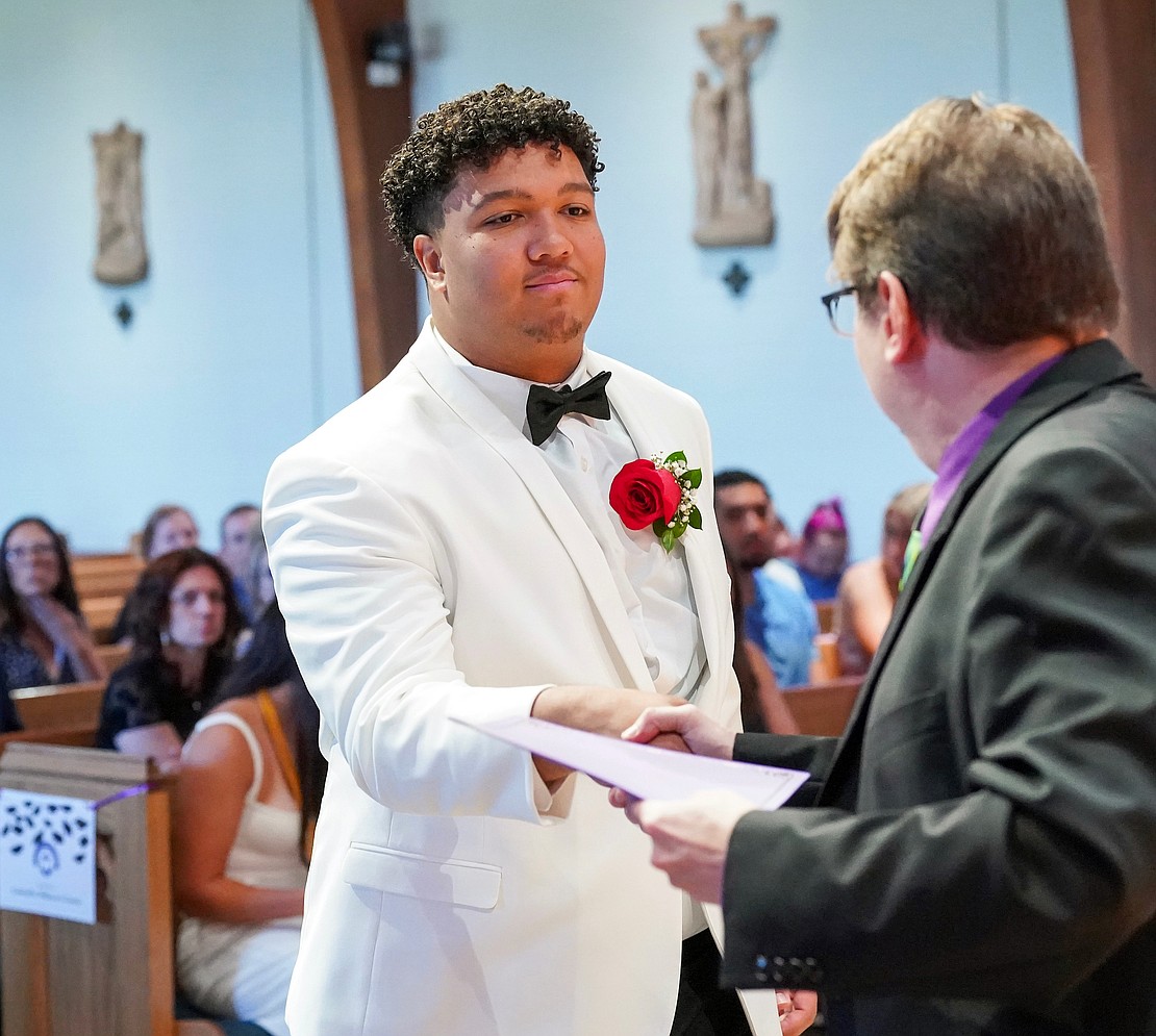 Graduate Adrian Mallory receives an award from principal Richard Harrigan during Catholic Central School's commencement exercises on June 27 at St. Ambrose Church in Latham. (Cindy Schultz photo for The Evangelist)