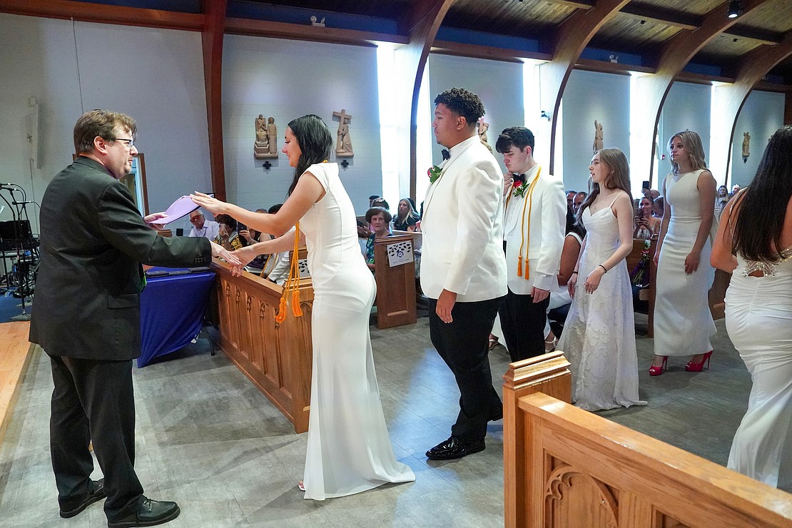 Graduate Emma Sagendorf (c.) and her class share in the Bernard W. McCormick Scholarship during Catholic Central School's commencement exercises on June 27 at St. Ambrose Church in Latham. Behind her (from l.) are Adrian Mallory, William Sandel, Emma Barno and Allesandra Gross. Principal Richard Harrigan (far l.) hands out the awards. (Cindy Schultz photo for The Evangelist).