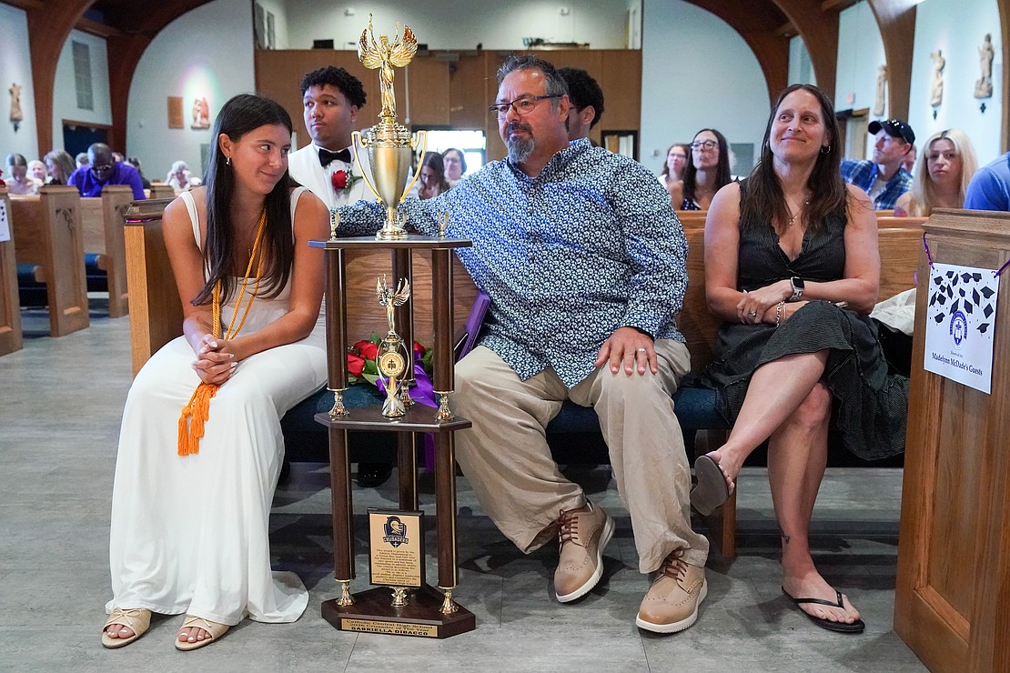 Graduate Gabriella Di Bacco (l.) sits with her parents, Guy and Audra, who are both basketball coaches, and her gigantic trophy for Crusader of the Year that she received for athletic excellence during Catholic Central School's commencement exercises on June 27 at St. Ambrose Church in Latham. (Cindy Schultz photo for The Evangelist)
