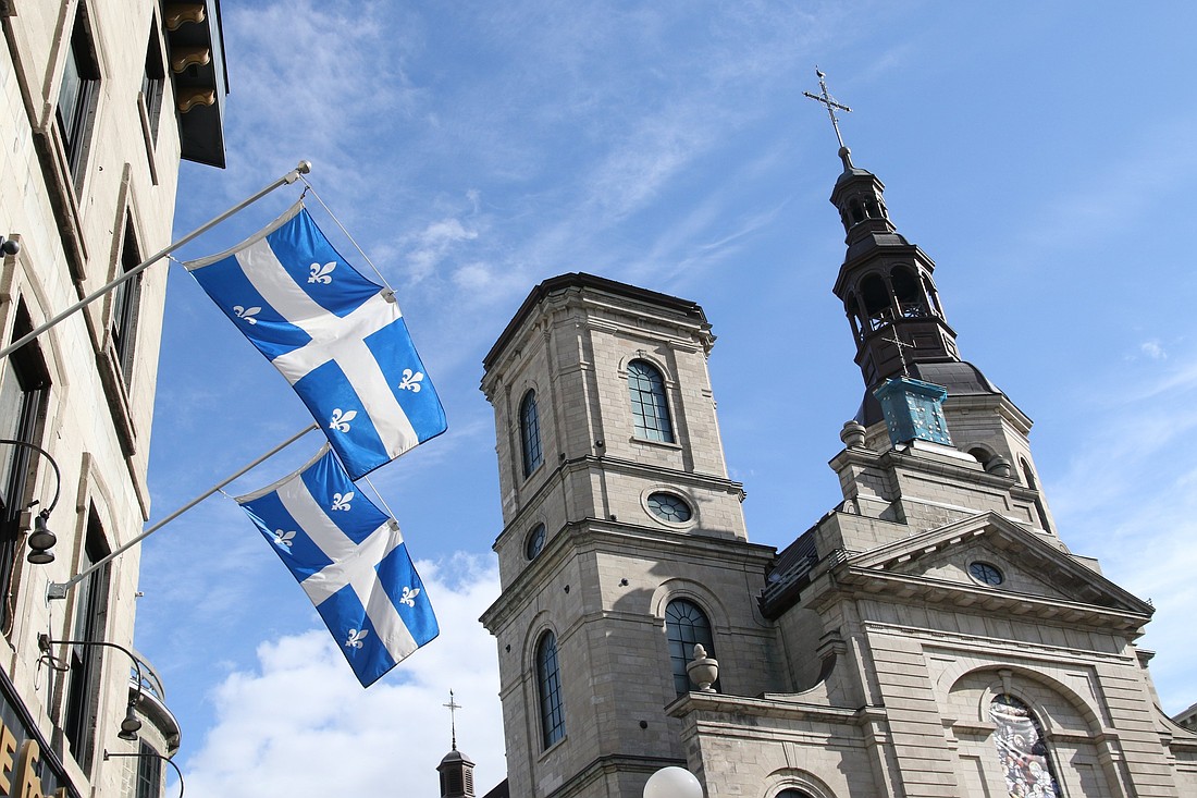 Quebec provincial flags are displayed outside a building across the street from the Cathedral-Basilica of Notre-Dame de Quebec in Quebec City in this file photo. The Archdiocese of Quebec, two educational institutions and an insurer will jointly pay a sum of $31.5 million to people who said they have been sexually assaulted by a member of the diocesan clergy or pastoral staff under the responsibility of the archdiocese since 1940. (OSV News photo/Gregory A. Shemitz)