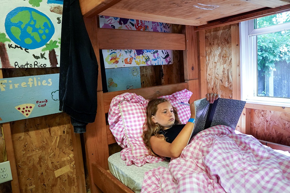 Evalynn Perreault, 10, lays in her lower bunk bed and writes in a journal on Aug. 4 at Camp Scully in Wynantskill. (Cindy Schultz photo for The Evangelist)