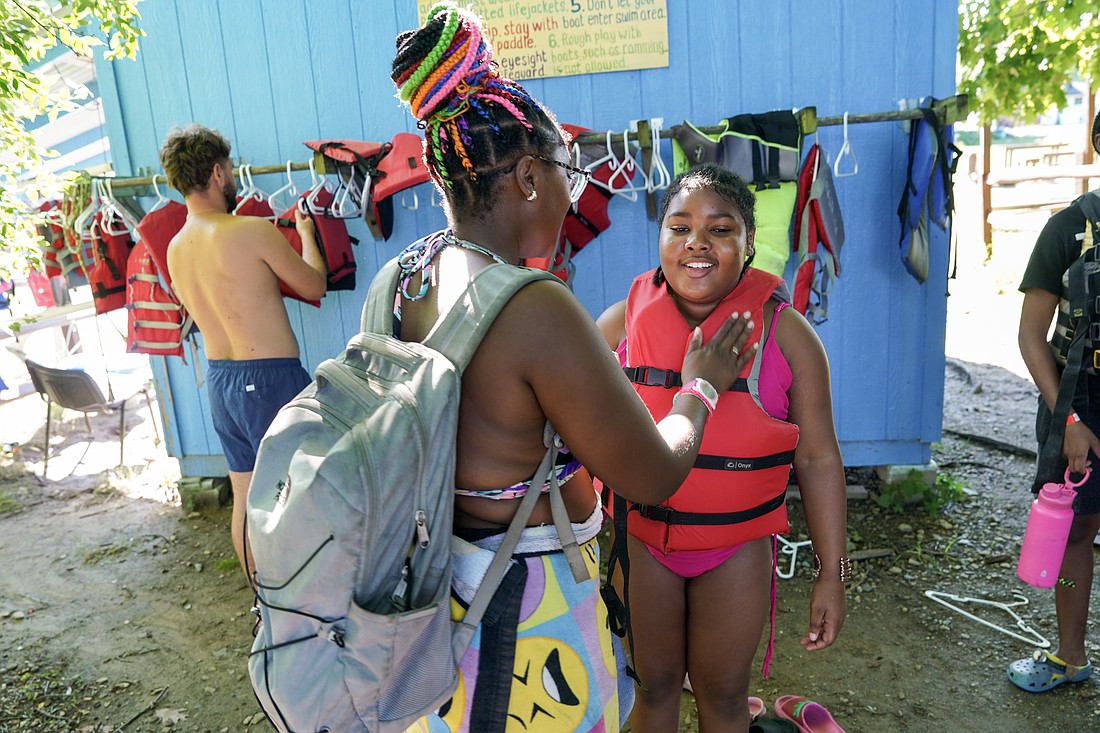 Camp counselor Victoria Rucker (l.) assists camper Brooklyn Barnes with her life vest on Aug. 4 at Camp Scully in Wynantskill. (Cindy Schultz photo for The Evangelist)