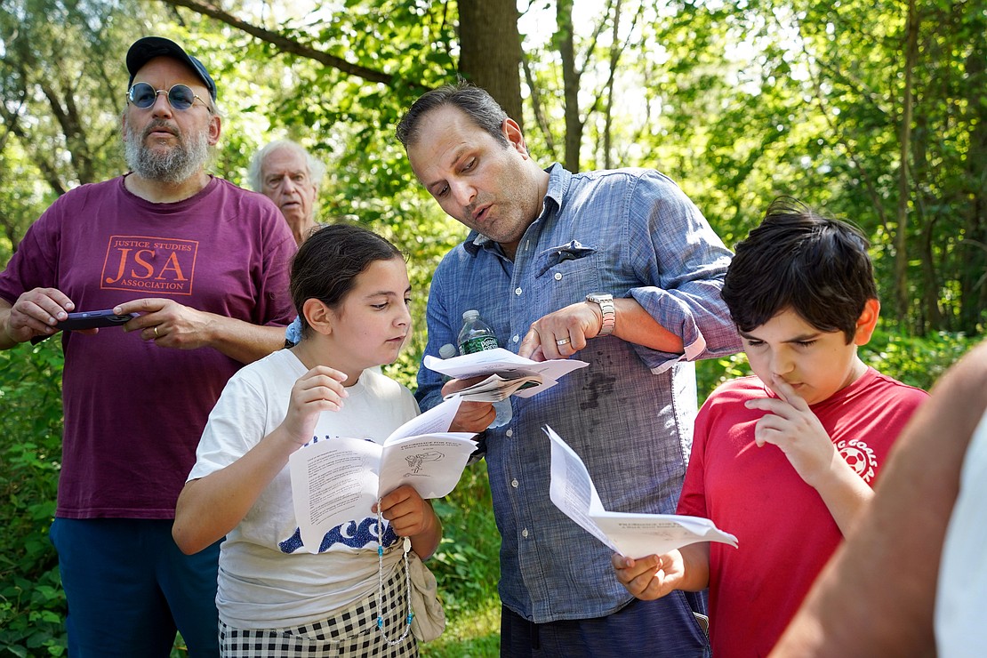 Remo Muscedere of Glenville (c.) a parishioner at St. Anthony, follows the program with his daughter Alexa Muscedere, 10, (l.) and son Max Muscedere, 10,  during the Pilgrimage for Peace on Saturday, Aug. 22. The event started at the National Shrine of the North American Martyrs in Auriesville. Participants, praying the rosary and singing songs, walked six miles to the Saint Kateri Tekakwitha National Shrine and Historic Site in Fonda. (Cindy Schultz photo for The Evangelist)