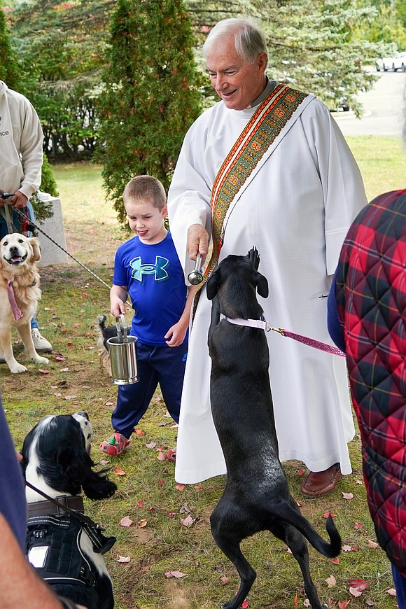 Deacon Richard Thiesen with the help of Joshua Obermayer, 5, walks among the pets to sprinkle them with holy water during the Pet Blessing and Adoption Clinic on Sunday, Oct. 4, at Christ Our Light Church in Loudonville. (Cindy Schultz photo for The Evangelist)