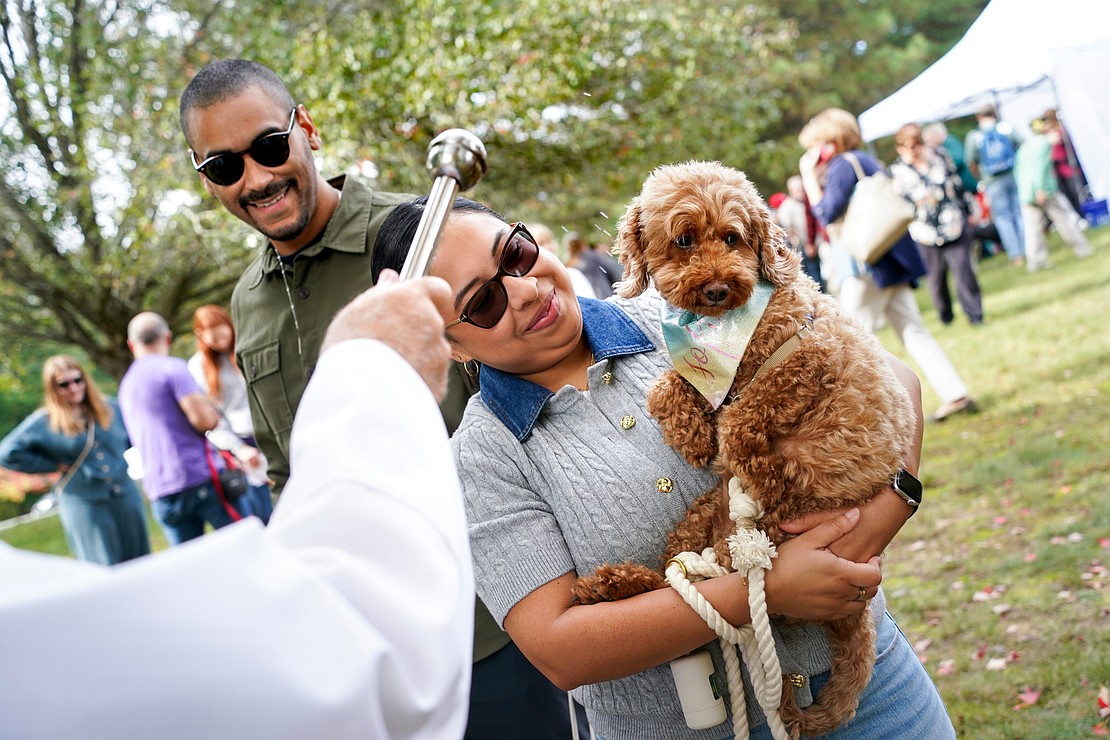 A couple holds their poodle mix to receive holy water during the Pet Blessing and Adoption Clinic on Sunday, Oct. 4, at Christ Our Light Church in Loudonville. (Cindy Schultz photo for The Evangelist)