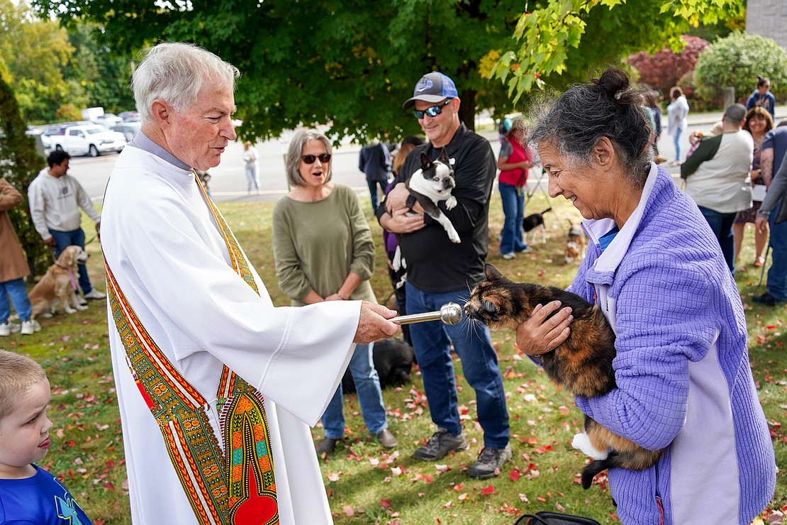A cat named Sunset sniffs the end of the aspergillum before Deacon Richard Thiesen sprinkles her with holy water during the Pet Blessing and Adoption Clinic on Sunday, Oct. 4, at Christ Our Light Church in Loudonville. Sunset’s owner Carol Hocheson, (r.), found the cat near a dumpster while she was traveling across the U.S.A. (Cindy Schultz photo for The Evangelist).