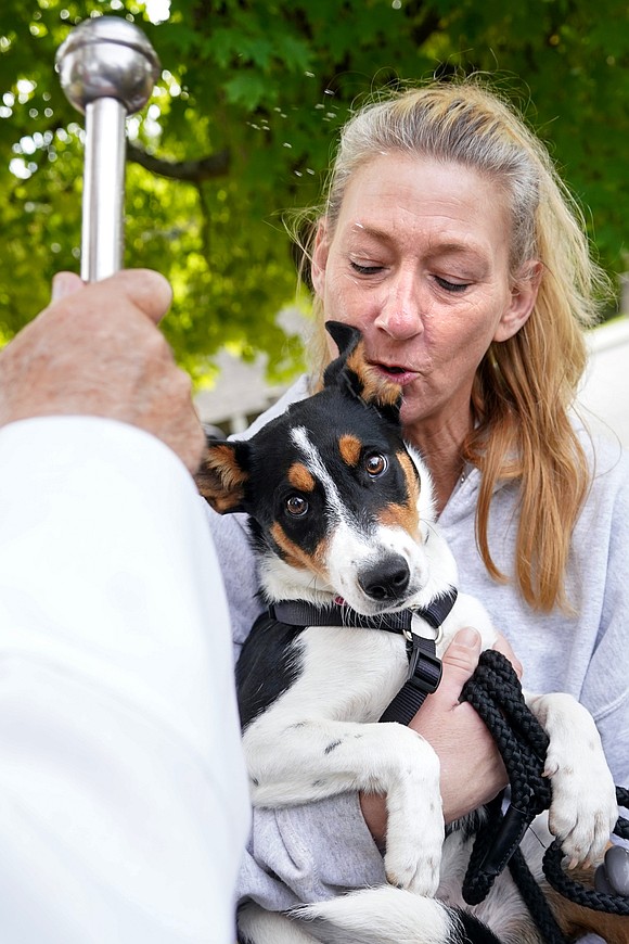 Stacey Gilchrist holds Angel, a border-collie mix, while receiving holy water from Deacon Richard Thiesen during the Pet Blessing and Adoption Clinic on Sunday, Oct. 4, at Christ Our Light Church in Loudonville. (Cindy Schultz photo for The Evangelist)