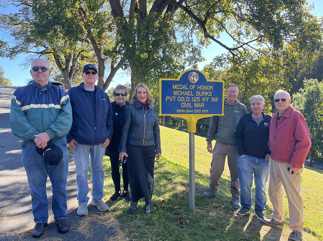 Jim Rivers (from l.), John “Jack” Welsh, Carole Weaver, Kelly Grimaldi, Kevin Sage, Sam Chiappone and Bill Sage stand in front of the newly restored Medal of Honor sign at the south entrance of St. Mary’s Cemetery in Troy. The old sign (seen below) was restored thanks to community efforts and sponsored by the C.R.A.B. Garrison #1954 club. (Emily Benson photos and photo provided)