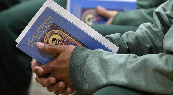 Bishop Edward B. Scharfenberger celebrated a special Christmas Mass for inmates at the Washington Correctional Facility in Comstock on Thursday, Dec. 19. Deacon Miguel Fabian, the facility’s chaplain, Father Rendell Torres and Deacon Ryan McNulty resided over the Mass, which was held in the facility’s gymnasium and attended by 33 inmates.   An inmate holding a bible.  Michael P. Farrell photos