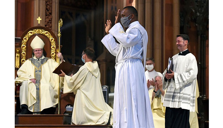 The combined Priesthood Ordination Rite and Diaconate Ordination Rite was celebrated by Bishop Edward B. Scharfenberger, with one man ordained to the priesthood and 13 men ordained to the Diaconate - eight men to the Permanent Diaconate and five men to the Transitional Diaconate - on Sept. 5 at the Cathedral of the Immaculate Conception in Albany.   Deacon Charles Onyeneke (c.) responds to cheers from the faithful as he is presented as candidate to the priesthood to Bishop Scharfenberger.  Photos by Cindy Schultz 