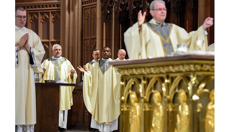 The combined Priesthood Ordination Rite and Diaconate Ordination Rite was celebrated by Bishop Edward B. Scharfenberger, with one man ordained to the priesthood and 13 men ordained to the Diaconate - eight men to the Permanent Diaconate and five men to the Transitional Diaconate - on Sept. 5 at the Cathedral of the Immaculate Conception in Albany.   Priest Charles Onyeneke (c.) and fellow priests join with Bishop Scharfenberger, who leads the congregation in saying the Our Father.  Photos by Cindy Schultz 