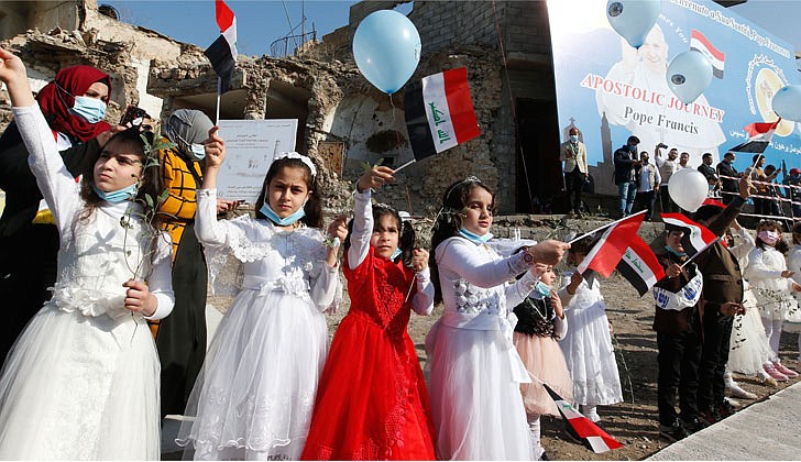 Girls hold Iraqi flags as Pope Francis participates in a memorial prayer for the victims of the war at Hosh al-Bieaa (church square) in Mosul, Iraq, March 7, 2021. (CNS photo/Paul Haring)