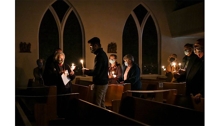 Marco Pantoja III, 18, (c.) lights candles for Easter Vigil Mass on April 3 at St. John the Baptist Church in Valatie. Pantoja acted as godfather to his family members when they were baptized during the Mass. (Cindy Schultz for The Evangelist)