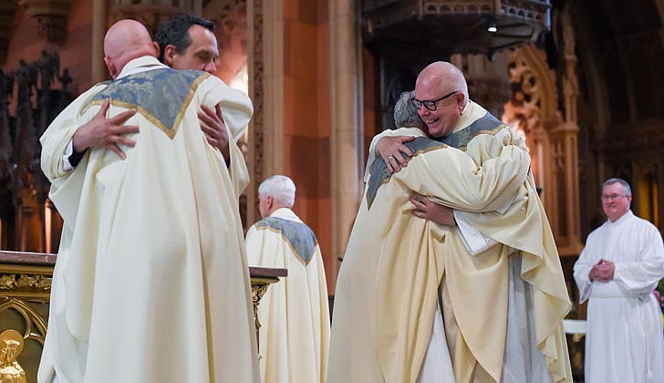 Newly ordained priests Russell Bergman (l.) and James O’Rourke (c. with glasses) embrace fellow priests for the Fraternal Kiss of Peace during their Ordination to the Priesthood on June 18 at the Cathedral of the Immaculate Conception in Albany.    Cindy Schultz photo for The Evangelist