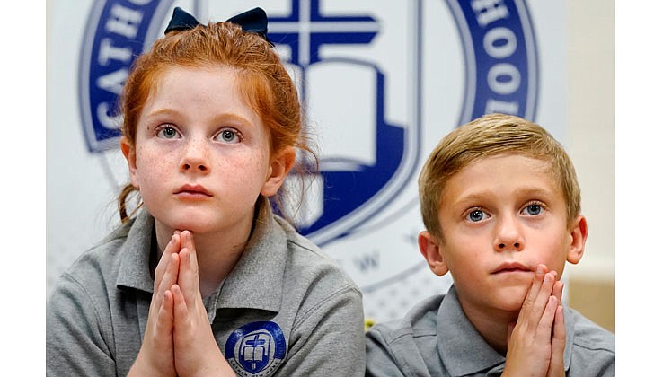 First-grader Charlotte Smith and second-grader Dylan Campito join in prayer during the official opening of Catholic Central School in Latham on Sept. 15.  Cindy Schultz photo for The Evangelist